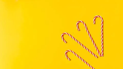 Red candy cane on yellow background. New Year and Christmas on beach on sea.  Stock Photos
