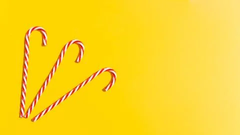 Red candy cane on yellow background. New Year and Christmas on beach on sea.  Stock Photos