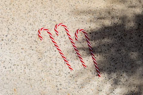Red candy canes on  textured background under palm shadows. Merry Christmas a Stock Photos