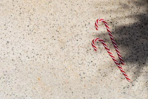 Red candy canes on  textured background under palm shadows. Merry Christmas a Stock Photos