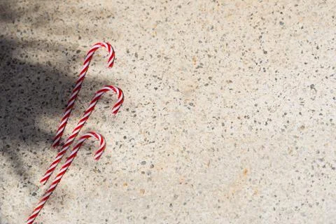 Red candy canes on  textured background under palm shadows. Merry Christmas a Stock Photos