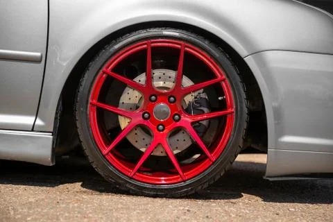 Red candy colored light alloy wheels on silver hatchback Stock Photos