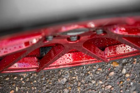 Red candy colored light alloy wheels on asphalt background. In raindrops Stock Photos
