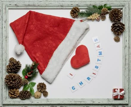 Red cap and heart in a frame with a Christmas inscription and paraphernalia Stock Photos