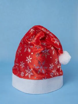 Red cap with silver pattern of Santa Claus with snowflakes on blue background 스톡 사진