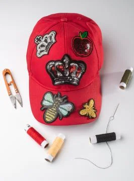 Red cap with various patches, threads, scissors and a neele on white background 스톡 사진
