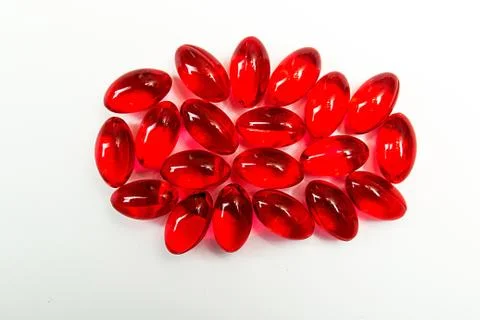 Red capcules with vitamins on white background. Stock Photos
