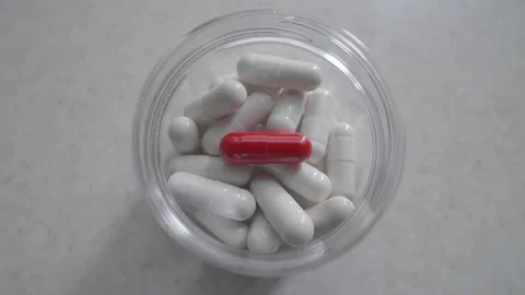 Red capsule pill on isolated white background. Medicine tablets inside bottle. Stock Footage 254462904