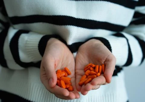 Red capsules in cupped hands close up Stock Photos