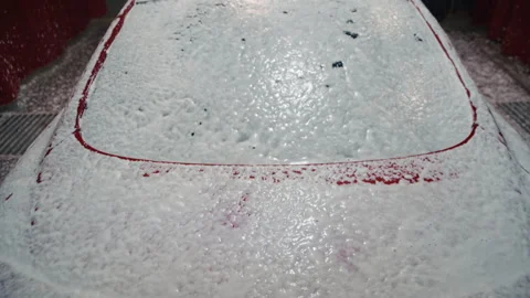 Red car covered in thick active foam at a self-service car wash 库存影片 325070980