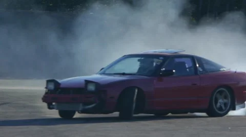 Red car drifting around corners leaving a trail of smoke. Stock Footage 59746804