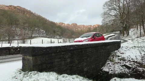 Red Car driven in winter snow over stone bridge Stock Footage 45532374