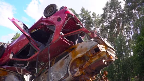 A red car is laying on its side in a pile of scrap metal Stock Footage 264323375