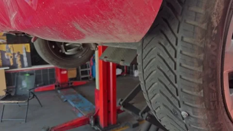 Red Car Raised on Two Post Lift Showing Front Wheel Stock Footage 343731325