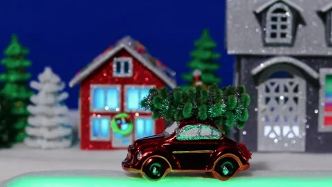 A red car slowly against the backdrop of a Christmas decorated village Stock Footage 306044283