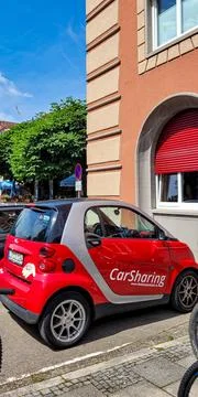 A red car Smart with a logo CarSharing stands of the parkingplace. A model of Stock Photos