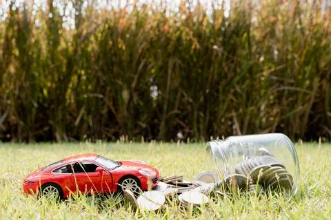 Red car on stack of coin on blurred green natural background. Saving money an Stock Photos