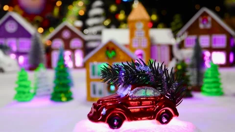 Red car on white surface moves against blurred background of Christmas town Stock Footage 292756065