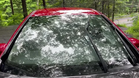 Red car windshield wipers wiping rain on windshield outdoors Stock Footage 340830885
