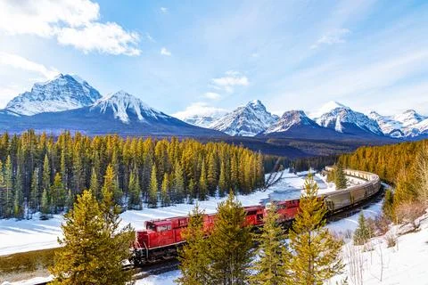 Red cargo train passing through Morant's Curve in Banff during Winter Stock Photos
