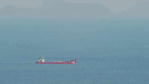 Red Cargo Vessel Sailing on Misty Tropical Morning Sea with Island Silhouettes Vídeo Stock 333436571