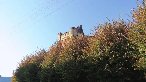 Red castle tower from behind trees with colorful leaves Vidéo 163679222