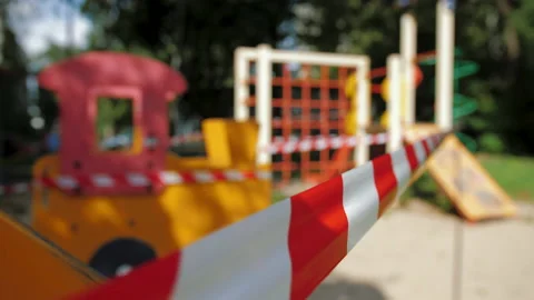 Red caution tape due coronavirus pandemic, children's playground is closed Video stock 137566790