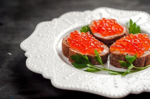 Red caviar on black bread with butter. Healthy food. Fish appetizer. dark 库存照片