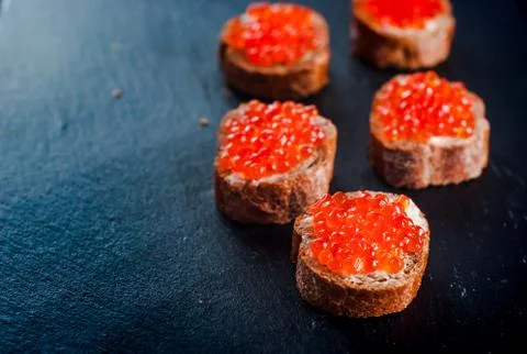 Red caviar on bread on slate background. 库存照片