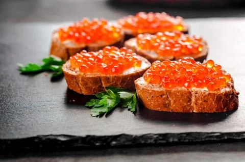 Red caviar on bread on slate background. Foto stock