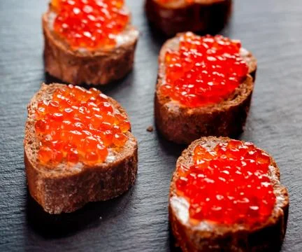 Red caviar on bread on slate background. 库存照片
