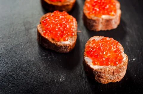 Red caviar on bread on slate background. Photos