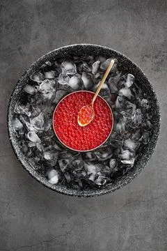 Red caviar in can on ice with spoon on grey background Stock Photos