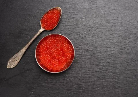 Red caviar of chum salmon in a metal spoon on a black background red cavia... Stock Photos