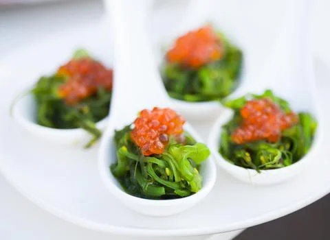 Red caviar close-up in white spoons on banquet Фото