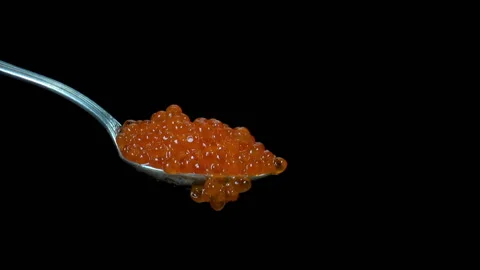 Red caviar drops from a spoon on a black Vídeo Stock 136567260
