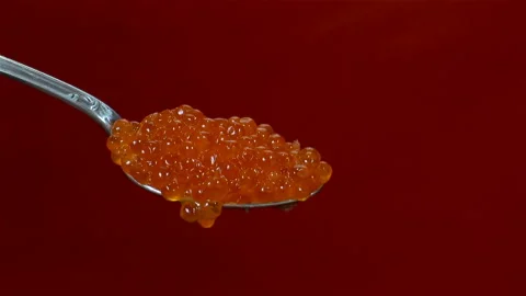 Red caviar drops from a spoon on a red Vídeo Stock 136567279