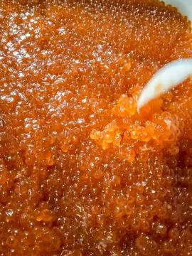 Red caviar in plastic container. Stirring with a plastic spoon o Stock Photos