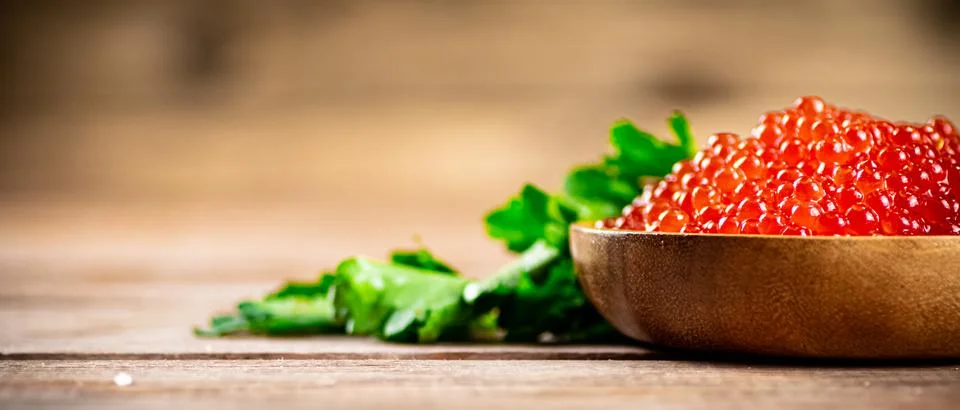 Red caviar in a plate on the table with parsley. Stock Photos