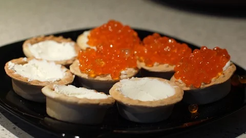 Red caviar is put with a spoon on tartlets with cottage cheese. Preparation of Stock Footage 119403758