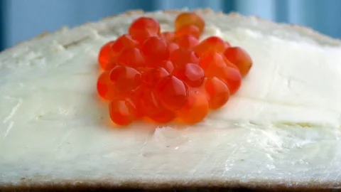 Red caviar runs down the butter on white bread Stock Footage 71127925