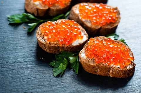 Red caviar on slate background Photos