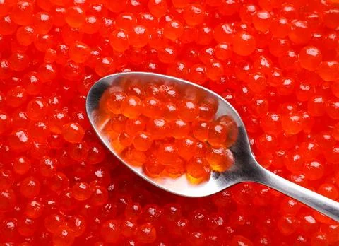 Red caviar in a spoon, background. Top view Stock Photos