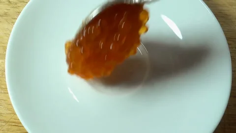 Red caviar with a spoon is placed in a white plate. Stock Footage 134590269