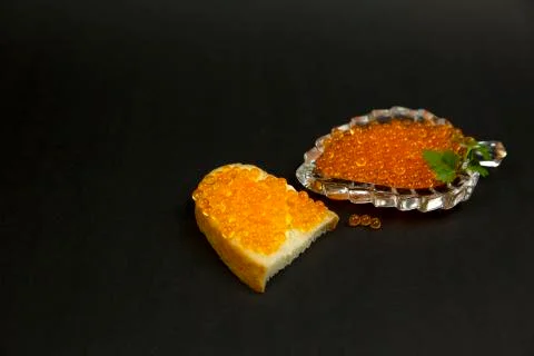 Red caviar spreading bread on a black background Stock Photos