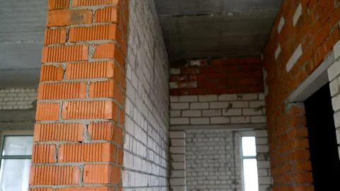 Red ceramic brick column and white silicate brick walls inside unfinished h.. Stock-Fotos