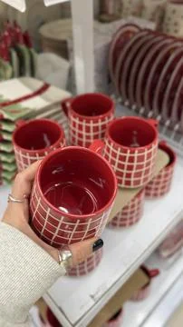 Red ceramic mugs with white grid pattern on display in a store setting for .. Stock Photos
