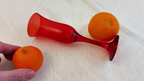 Red Champagne Flute with Two Oranges on White Textured Cloth Video stock 327587127