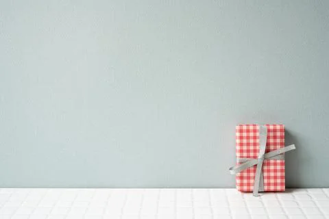 Red check pattern gift box on white tile table. gray wall background Foto stock