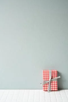 Red check pattern gift box on white tile table. gray wall background Foto stock